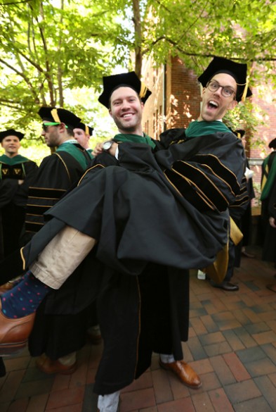 Ryan Adams gives a lift to fellow School of Medicine graduate Ben Hooe at last Friday’s Commencement ceremony. (photo by Anne Rayner)