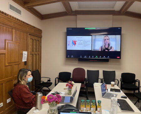 Janna Landsperger, MSN, RN, ACNP, seated, helps conduct the ACNP/PA Critical Care Boot Camp from a conference room in Medical Center North. Presenting on screen is Allison Wynes, a nurse practitioner at University of Iowa Hospitals and Clinics. 