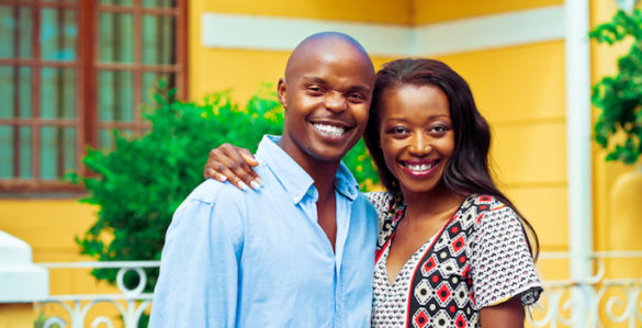Happy african couple embracing in front of their new house.