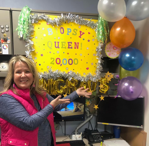 Krista Kuhnert-Gainer, ACNP, shows off the sign her colleagues made to celebrate her reaching 20,000 bone marrow biopsies performed.