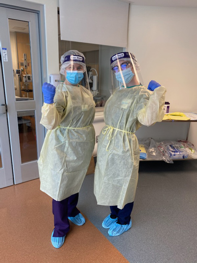 Beverly Woodward, MSN, RN, (left) and Morgan Lima, RN, pose in their personal protective gear in the anteroom of the CRC Communicable Disease Response Unit, prior to giving a newly diagnosed COVID-19 patient a monoclonal antibody infusion. 