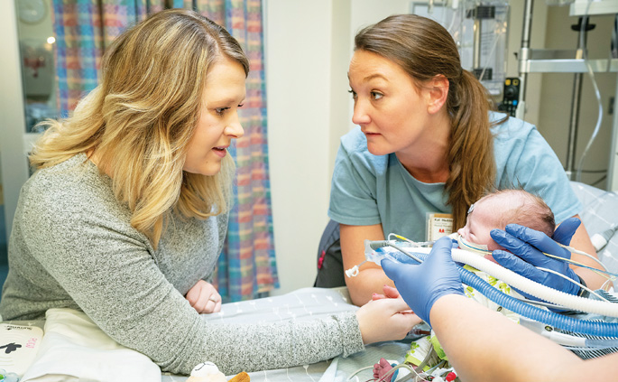 Emily Bilbrey, left, engages her son Chandler as pediatric physical therapist Kat Hedden, PT, performs an early mobility intervention in the pediatric intensive care unit.