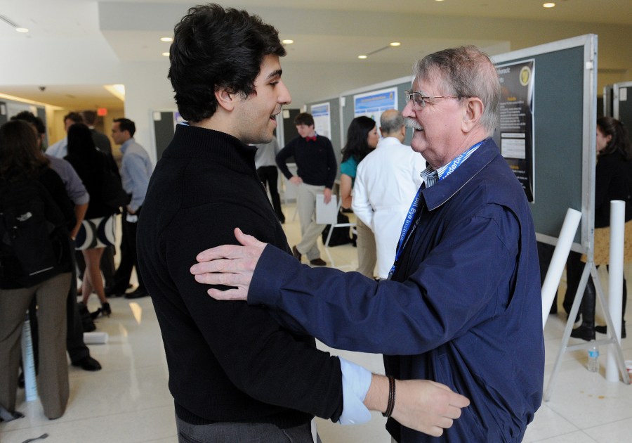 Denis O'Day, M.D., right, greets medical student Alejandro de Feria  during poster presentations for the Emphasis program. This is O'Day's last year as director. (Photo by Joe Howell)