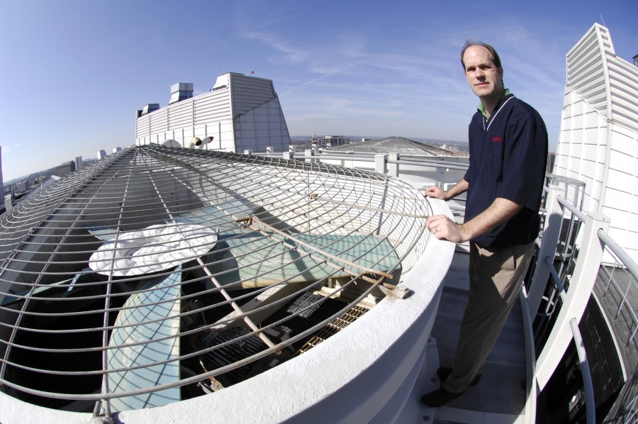 Mike Gable, an engineer with Space & Facilities Planning, examines the air intake fans atop MRB III. (photo by Anne Rayner)