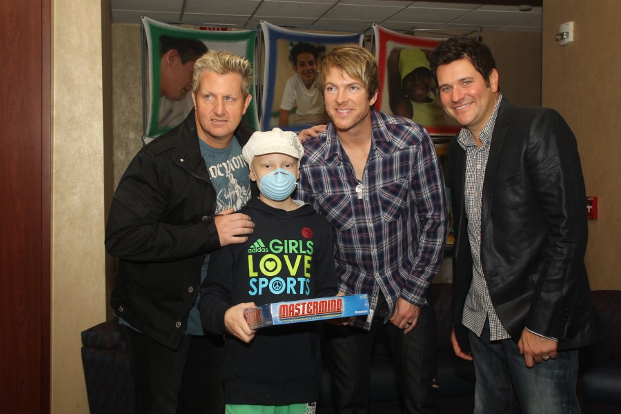 Patient Anna Martin, 10, poses for a photo with band members, from left, Gary LeVox, Joe Don Rooney and Jay DeMarcus.