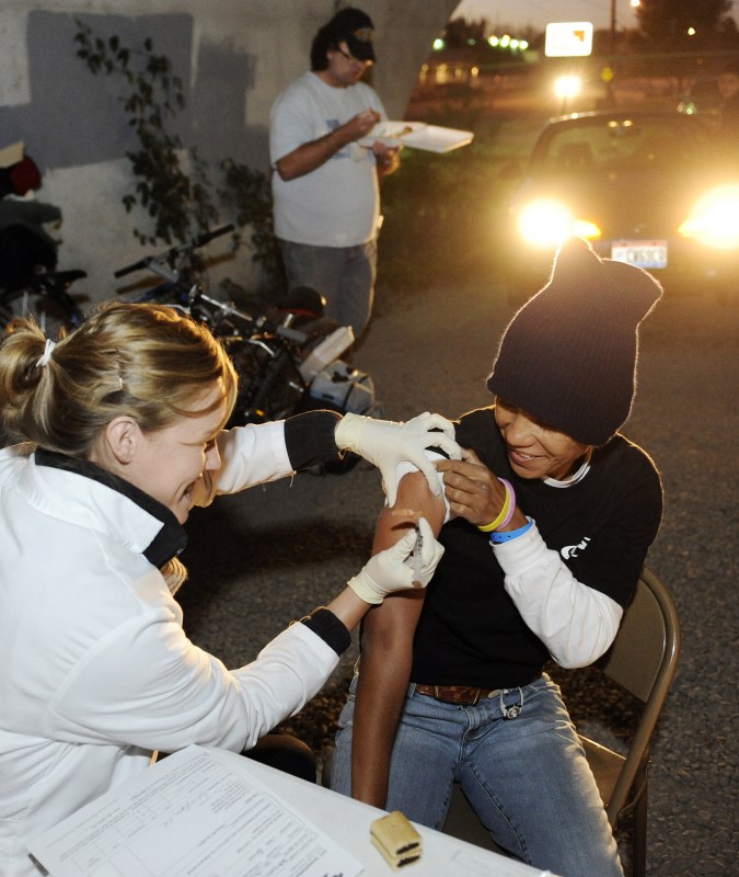 Nani Kalama receives a flu shot from Jennifer Prager, R.N., at the special clinic held under the Jefferson Street Bridge downtown. (photo by Joe Howell)