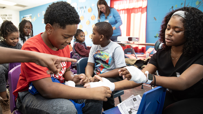 Cayden Starks, 9, wraps Shama Dufresne’s, a Vanderbilt University medical student’s, hand with gauze at the Future is NOW event. (photo by Erin O. Smith)