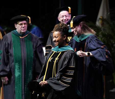 Medical student Kia Quinlan,MD, receives her academic hood from Amy Fleming, MD, MHPE, as C. Wright Pinson, MBA, MD, left, and Donald Brady, MD, look on.
