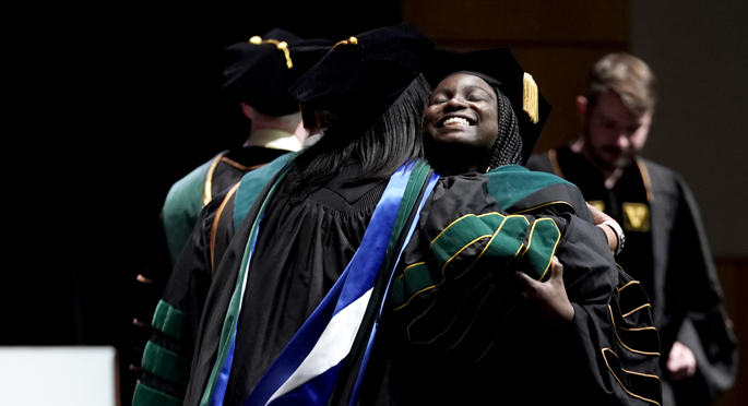 Smotochukwu Ukwuani, MD, gets a hug after receiving her diploma at the School of Medicine ceremony.