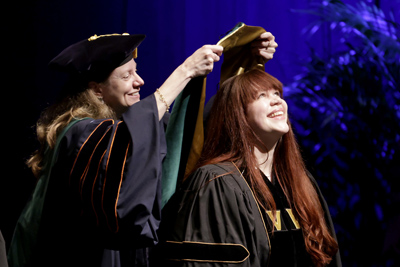 Kelsey McNew receives her VUSM academic hood from Amy Fleming, MD, MScHPE.
