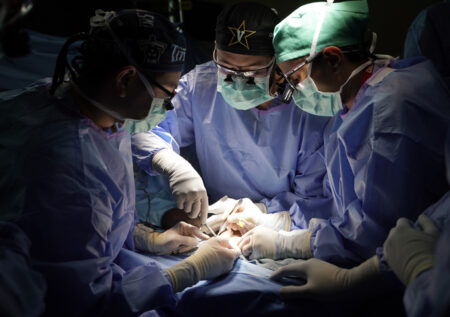 From left, Hand and Upper Extremity fellow Jonathan Yu, MD, Orthopaedic resident Eric Dilbone, MD, and Orthopaedic surgeon Mihir Desai, MD, work together during Clearissa Griggs’ hand surgery.