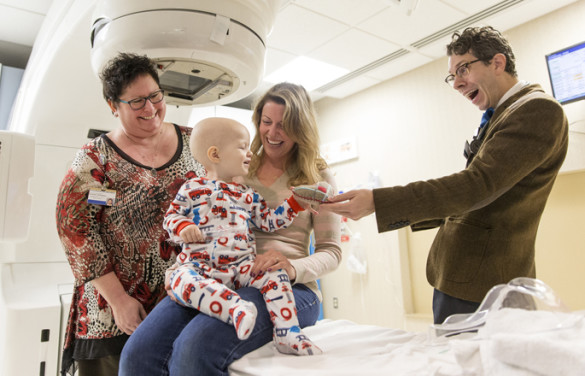 Rachel McDowell, APRN, left, and Mark Stavas, M.D., present a “Heart to Hold” to Vanderbilt-Ingram Cancer Center patient Finn Schafran and his mother, BrandiLee Schafran. (photo by Joe Howell)