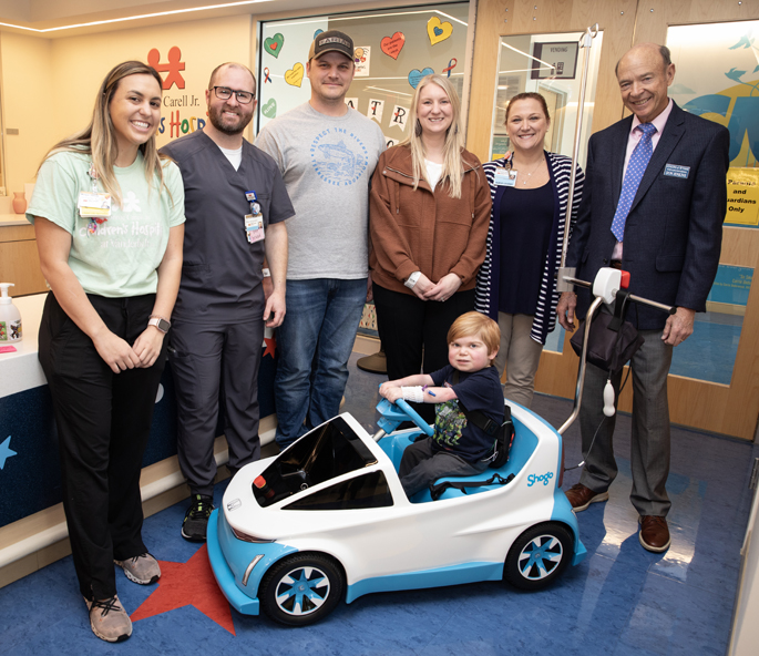 Grant Cole, 7, tests out the new Shogo, surrounded by, from left, Morgan Perrotti, MS, CCLC, child life specialist; John David Hughes, MMHC, RN, NE-BC, Pediatric Cardiology unit manager; parents Josh and Lea Cole; Amber Hawkins, MSN, PMHNP-BC, clinical staff leader, PCARD; and Don Jenkins, president of the Tennessee Honda Dealers. (photo by Erin O. Smith)