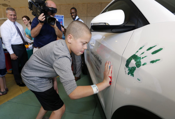 Gabe Daniels, 12, who is battling cancer with the help of Monroe Carell Jr. Children’s Hospital at Vanderbilt, places his painted handprint on the official Hyundai Hope on Wheels vehicle as a symbol of his journey. (photo by Steve Green)