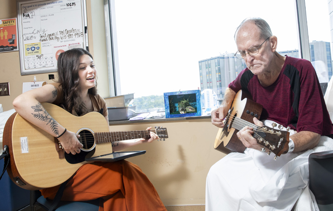 Music therapist Tori Langham, MT-BC, works with patient Kevin Keach in the adult Palliative Care unit. (photo by Susan Urmy)