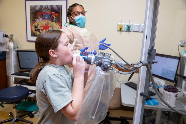 Registered respiratory therapist Natasha Vanderbilt, RRT, encourages 10-year-old Kate to exhale a complete breath during a lung function test in the Pediatric Pulmonary Medicine clinic. (photo by Susan Urmy)