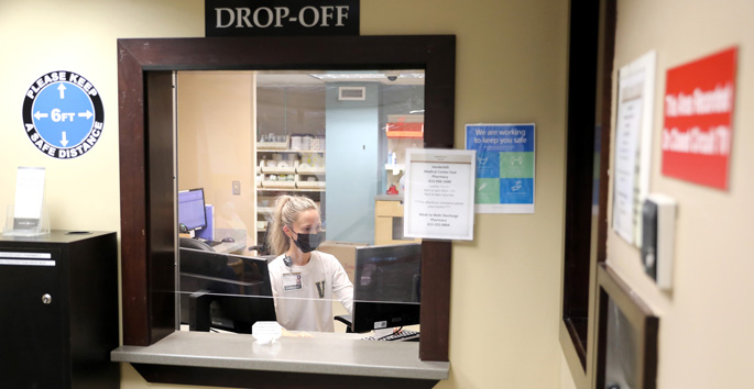 Alison Elliott, PharmD, a pharmacist at the Medical Center East Pharmacy, sits at the designated service window where patients will pick up prescriptions after hours. The Medical Center East pharmacy has extended its hours to operate 24 hours a day, seven days a week.