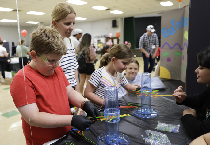 Jack Phillips, 10, and his sister Francine, 8, with help from graduate student Isabella Sirit, right, tackle an activity that demonstrates how epithelial cells protect themselves from microbes, as their mother, Amanda Phillips, watches.