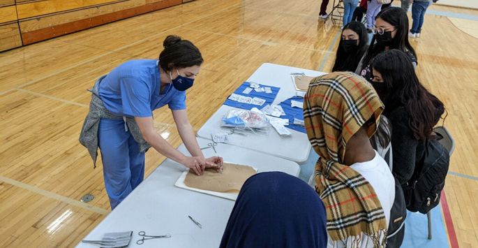 VUSM resident Carolina Gomez Grimaldo, MD, demonstrates how to suture for Metro Nashville Public Schools students during a recent event where residents, fellows and medical students talked about why and how they chose to become physicians.