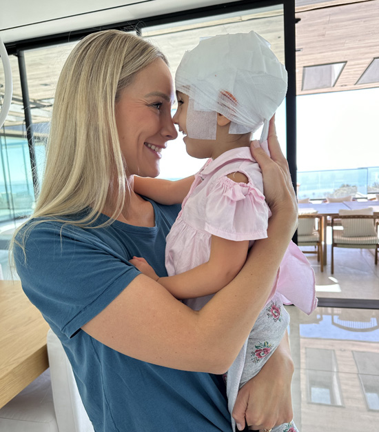 Monica Elnekaveh hugs her daughter Eleanor, who is wearing a gauze cap to keep the adhesive-attached electrodes and wires in place during a 72-hour ambulatory electroencephalogram (EEG), used in the diagnosis of epilepsy, head injury and other brain disorders. (photo courtesy of Monica Elnekaveh)