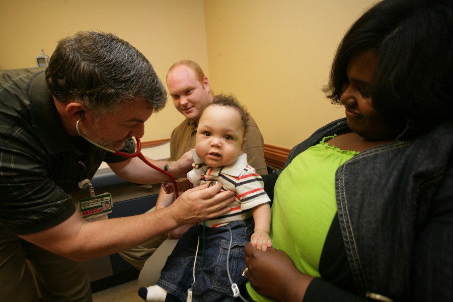 Brian Carter, M.D., left, examines Nathan Durham Jr. while his parents, Nathan and Danielle, look on during a follow-up visit at the Monroe Carell Jr. Children’s Hospital at Vanderbilt. (photo by Daniel Dubois)