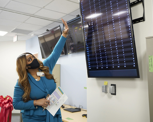 Kirbee Miller, MS, examines the wall-mounted monitor boards in the new Operational Control Center.