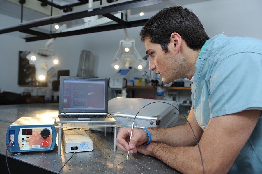 Graduate student Constantine Paras examining the parathyroid detector, which was assembled from off-the-shelf hardware and is compact enough to fit into a briefcase. (photo by Joe Howell)