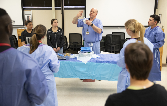Christopher Brown MS, CC-P, Strategic Medical Asset Readiness Training (SMART) program manager, teaches a scrub and sterile procedure class for a rotation of military medical providers. (photo by Erin O. Smith)