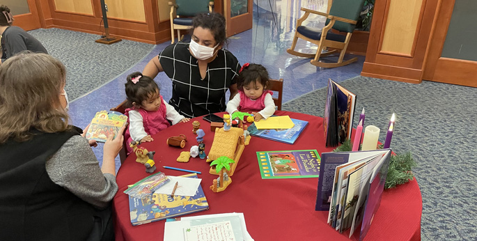 Twins Zara and Zoe Perez, 18 months, and their mother, Rosa Eastaneda, interact with the characters from the Nativity during Sacred Celebrations in the chapel at Monroe Carell Jr. Children’s Hospital at Vanderbilt while listening to Chaplain Lisa Hermann read a book.