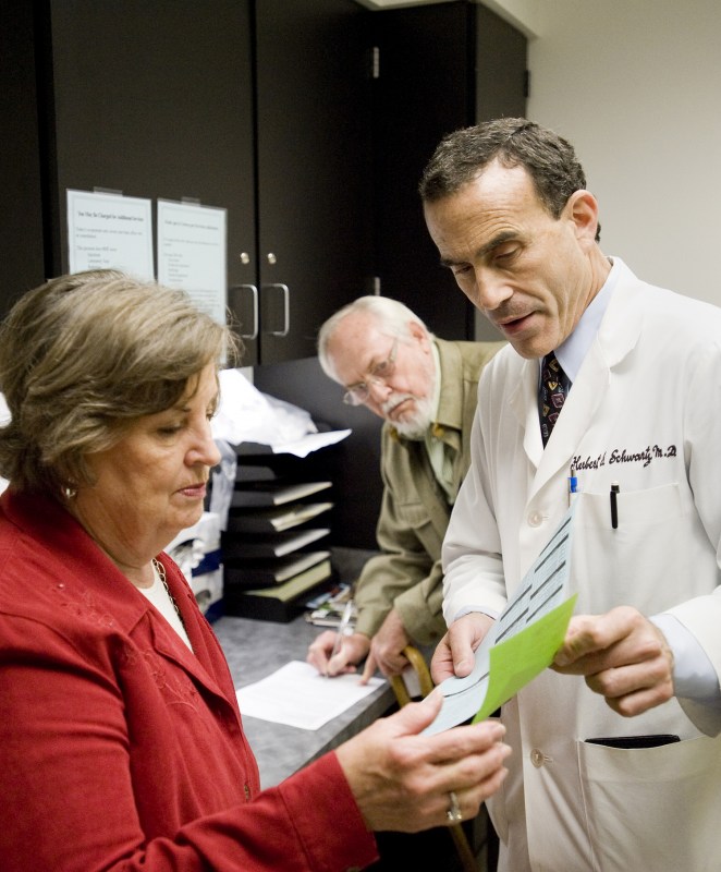 Schwartz talks with John Saunders, a longtime patient, and his wife, Rose. (photo by Joe Howell)