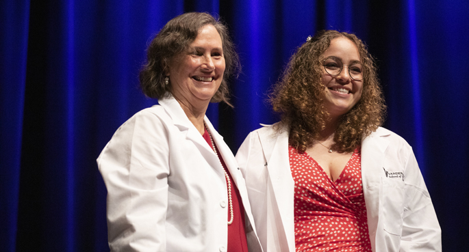 New graduate student Kaitlyn Gallagher, right, is all smiles after Kathy Gould, PhD, senior associate dean for Biomedical Research Education and Training, helps her into her lab coat. Admitted to the Interdisciplinary Graduate Program (IGP) in Biological and Biomedical Sciences, Gallagher was among 117 new PhD students welcomed during the recent ceremony in Langford Auditorium. (All photos by Erin O. Smith)