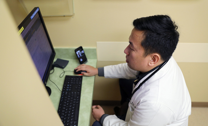 Francis Balucan, MD, a physician with Vanderbilt Familiar Faces team, speaks with a patient via a video conference call while looking over the patient’s information at the Eskind Diabetes Center. 