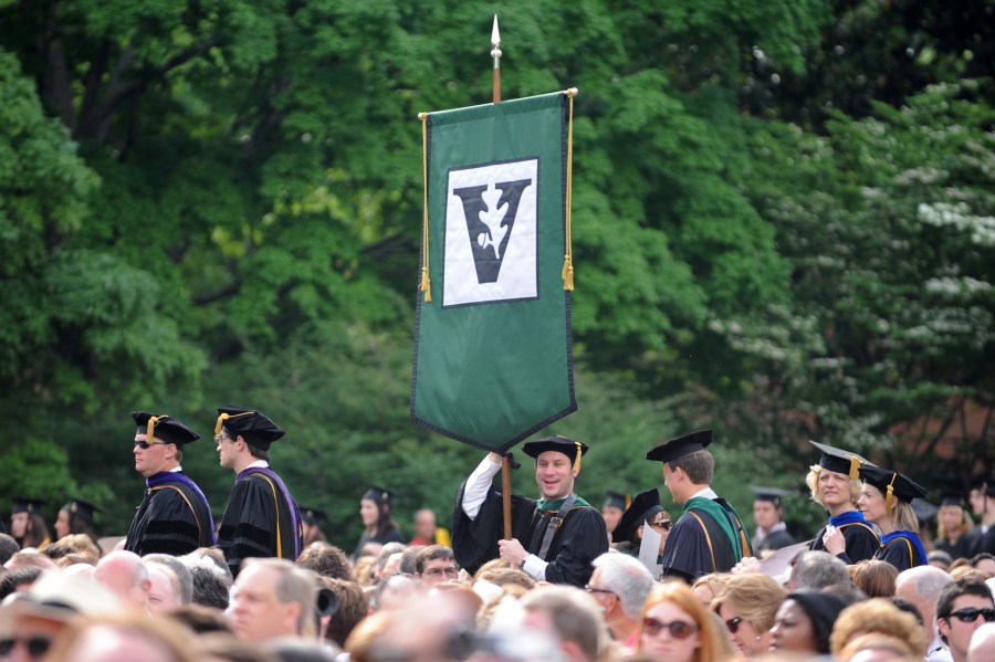 Class president Eli Zimmerman carries the School of Medicine flag at Commencement. (photo by Joe Howell)