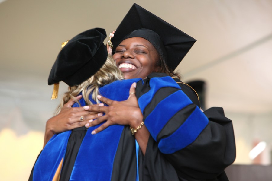 Brittany Briggs, right, gets a hug from Amy Bull, Ph.D., MSN, at the Nursing School ceremony. (photo by Susan Urmy)