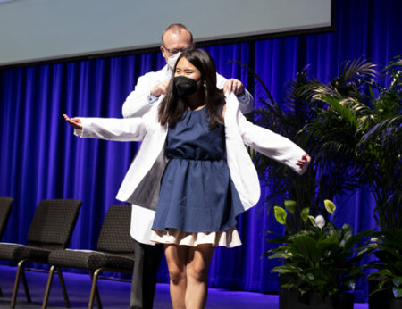 Jeff Balser, MD, PhD, helps Jia Brigette put on her white coat at last week’s ceremony.