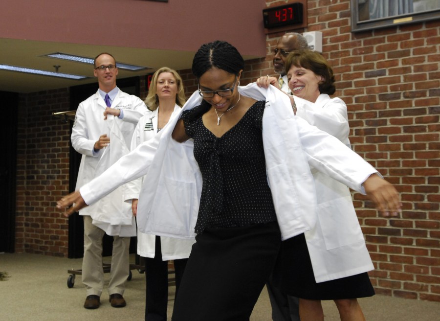 Uzoamaka Ugochukwu receives her coat from Scott Rodgers, M.D., left, Kimberly Lomis, M.D., George Hill, Ph.D., and Bonnie Miller, M.D. (photo by Anne Rayner)
