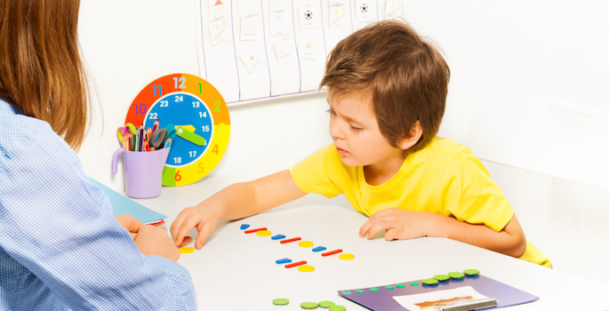 boy arranging colorful objects with therapist