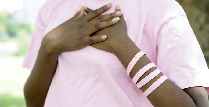 African American woman in pink crossing her hands over her breast