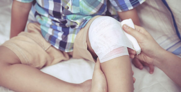 Adult bandaging a child's knee