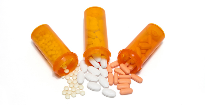 Three overturned prescription bottles spilling out three kinds of pills, symbolizing combination therapy