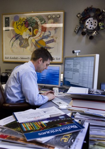 Crowe in his office, surrounded by scientific journals and some favorite pieces of artwork, including a print by Vasily Kandinsky and outsider art by Hawkins Bolden. (photo by Dana Johnson)