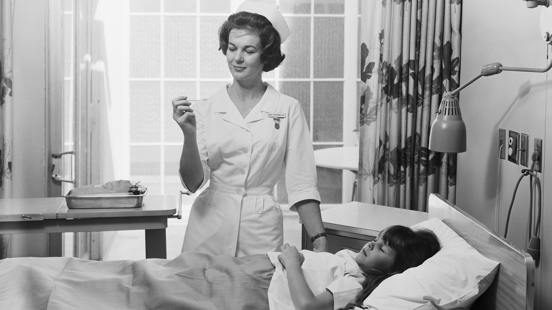 Black and white photo of nurse and child in hospital from the 1960s
