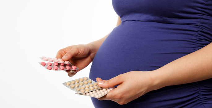Pregnant woman holding pill pack