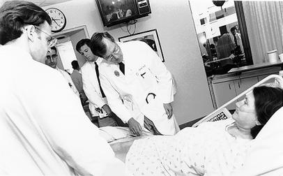 Dr. John Sergent examines patient Linda Holder on rounds with medical students (from left) Daniel Penn, Lawrence Berman and Omer Shedd.