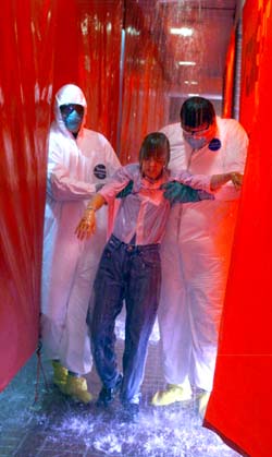 Keith Robinson and Johnny Vanderpool of Environmental Health and Safety assist patient Lara Tosh through the decontamination shower. (photo by Dana Johnson)