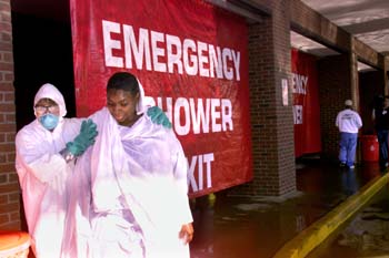 Kendra Coleman is led out of the decontamination shower area by Kelley Work of Environmental Health and Safety. (photo by Dana Johnson)