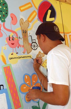 Giro Gabayoyo, R.N., adds artwork representing Urology and Orthopaedics to the mural during Tunnel Palooza last week. 
photo by Dana Johnson