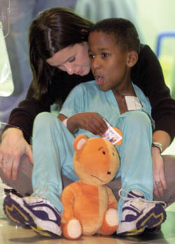 Patient Rodrick Payne, 8, talks with Mimmie McKnight of Child Life about his Tangerine Bear. (photo by Dana Johnson)