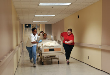 Jannah Branch-Smith, R.N., left, and Faith Reed, R.N., M.S.N., right, move patient Nathan Goolsby through the tunnel to the new Burn Center last Friday.
photo by Dana Johnson