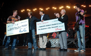 Rascal Flatts’ Gary LeVox, left, Joe Don Rooney and Jay DeMarcus, right, presented Jim Shmerling and Harry Jacobson, M.D., with proceeds from the group’s concert in September, which benefitted the Monroe Carell Jr. Children’s Hospital at Vanderbilt. 
photo by Dana Johnson